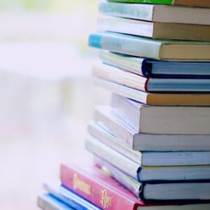 A tall stack of colorful hardcover books on a table indoors, perfect for library-themed concepts.