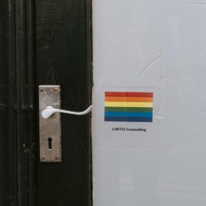 Colorful LGBTQ symbol of lesbian gay bisexual and transgender pride on wall near door knob on black door of counselling building