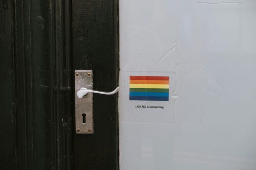 Colorful LGBTQ symbol of lesbian gay bisexual and transgender pride on wall near door knob on black door of counselling building